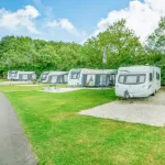 touring caravans on neat hard standing pitches surrounded by green grass and trees