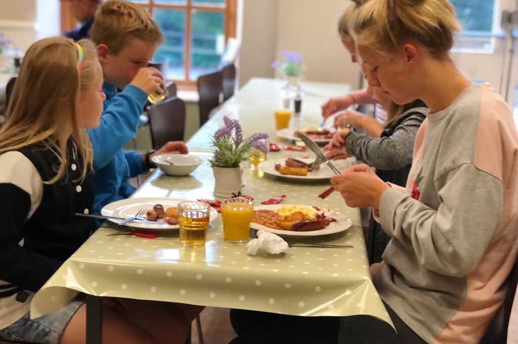 family sat at cafe table eating a cooked breakfast