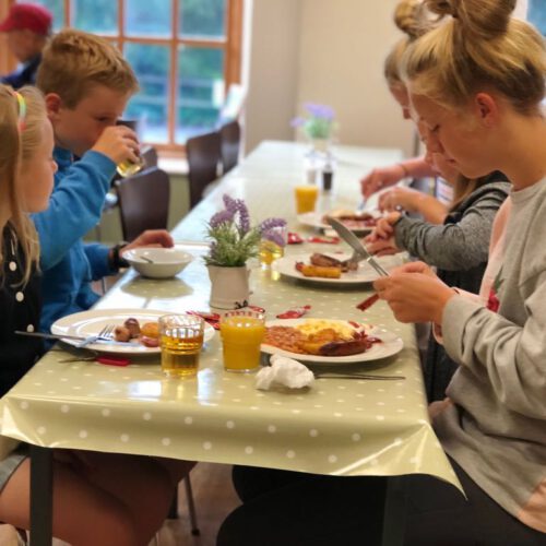 family sat at cafe table eating a cooked breakfast