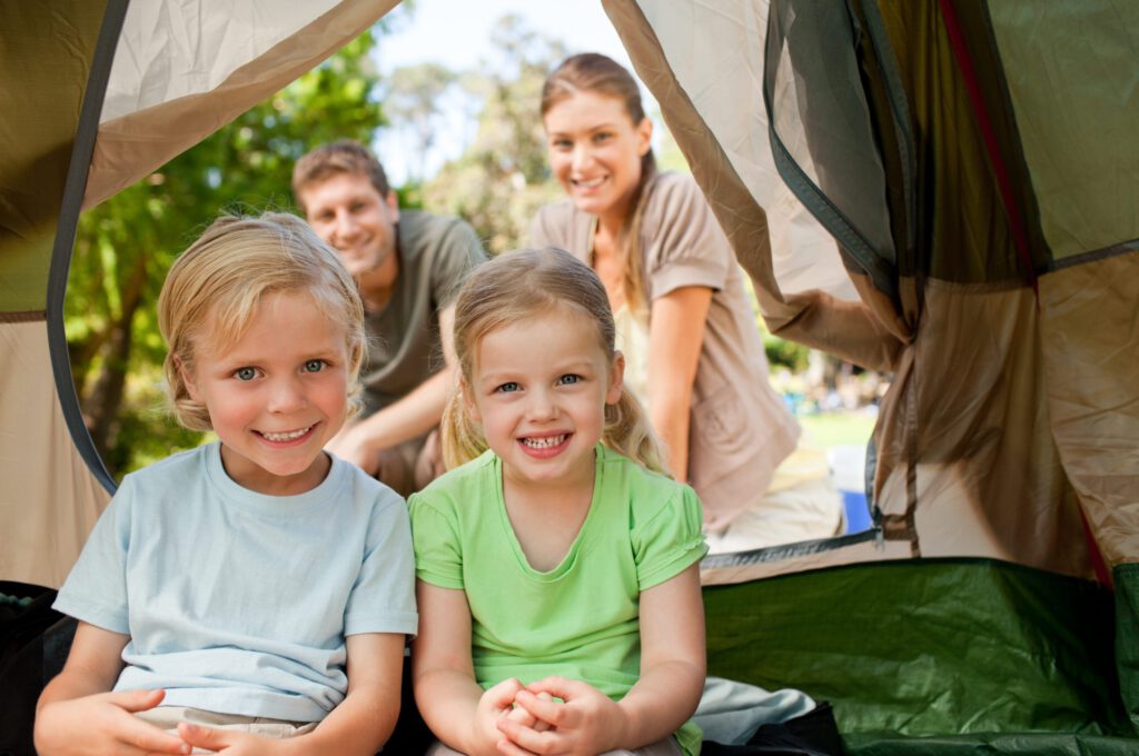 couple with two young children happily camping in tent