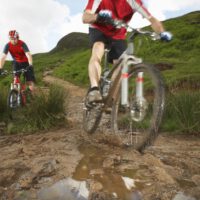 two cyclists on mountain bikes on muddy nature trail