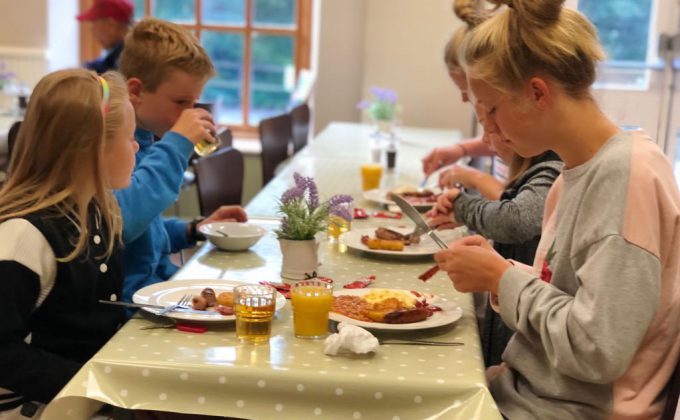 family with children eating a cooked english breakfast in Cote Ghyll Mill dining room