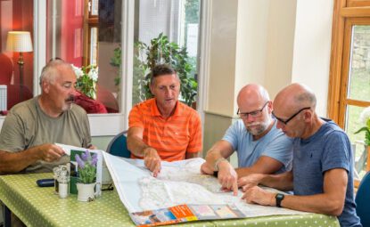 4 men looking at map whilst sat at dining table in Cote Ghyll Mill