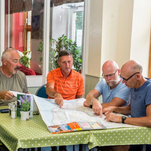 4 men looking at map whilst sat at dining table in Cote Ghyll Mill