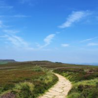 small winding moorland footpath beneath bright blue sky