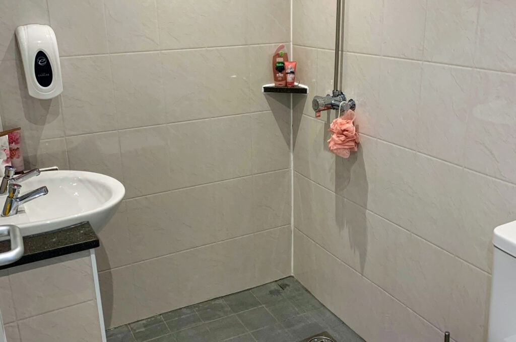 fully tiled shower room with sink and toilet