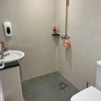 fully tiled shower room with sink and toilet